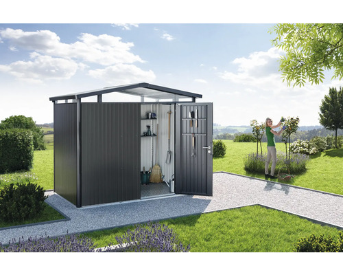Abri de jardin métallique ouvert avec des outils de jardin et une femme travaillant dans le jardin.