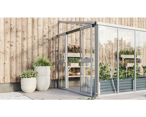 Serre avec plantes et pots devant un mur en bois