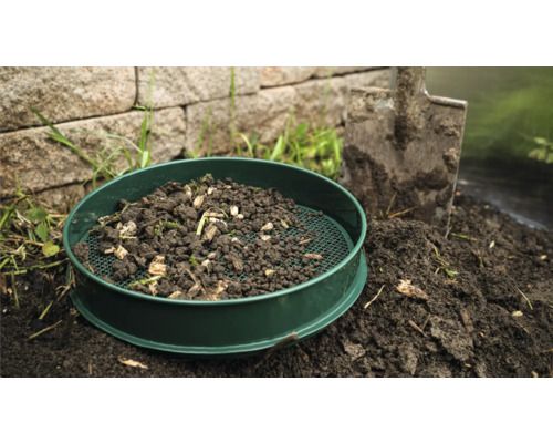 Tamis de jardin avec terre et pelle dans le jardin