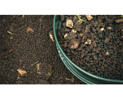 La terre est tamisée à travers un crible de jardin