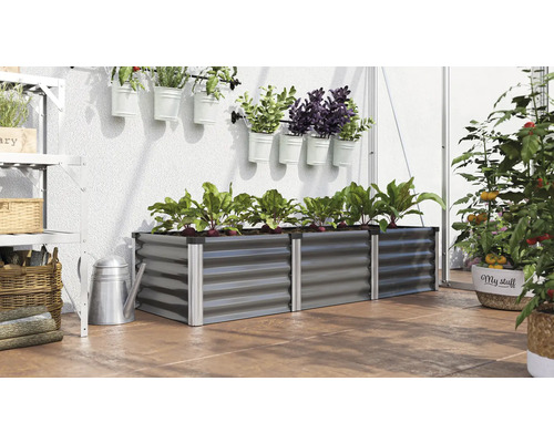Scène avec un potager surélevé en métal planté de légumes, avec une étagère murale et des plantes