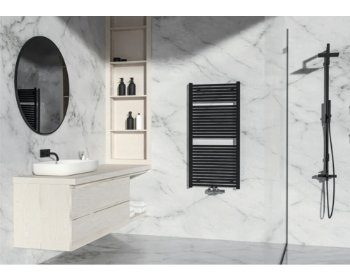 Helles Badezimmer mit Waschbecken, Spiegel, Handtuchwärmer und Dusche vor Marmorwand