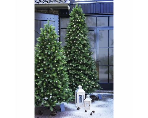 Deux arbres de Noël artificiels illuminés à l'extérieur avec des lanternes et des pommes de pin
