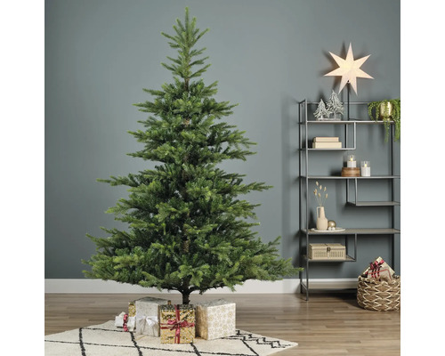 Sapin de Noël artificiel avec cadeaux de Noël sur un tapis dans la pièce.