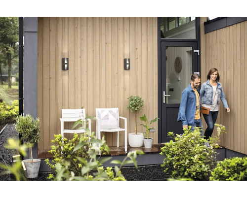 Façade de maison avec luminaires extérieurs, chaises, plantes et porte d''entrée