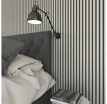 Scène de chambre à coucher avec lit, table de chevet et applique murale devant un mur rayé