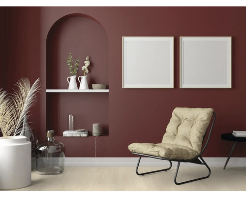 Wohnzimmer mit Sessel, Dekoration und Bilderrahmen an einer bordeauxroten Wand