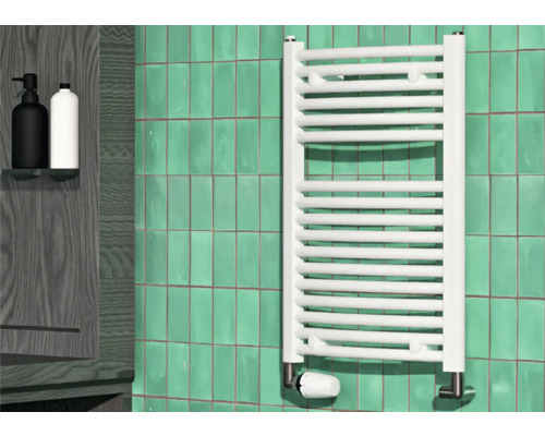 Salle de bains avec radiateur blanc, mur carrelé et deux distributeurs de savon