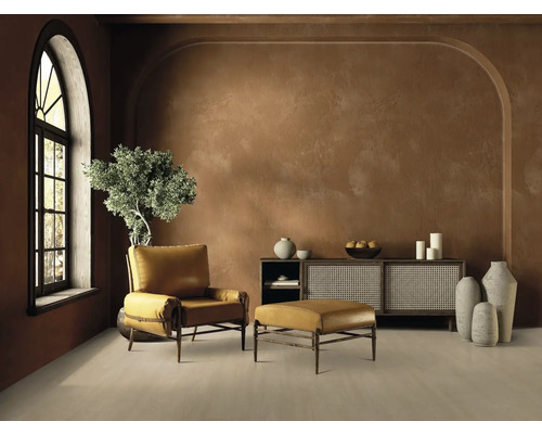 Wohnzimmer mit Sessel, Fußhocker, Sideboard und Dekoration in warmen Erdtönen.