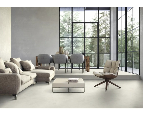 Helles Wohnzimmer mit Sofa, Sesseln, Esstisch und großem Fenster mit Blick auf Bäume