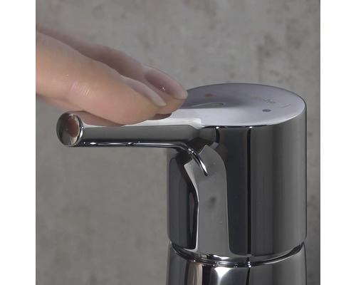 Gros plan d''un robinet chromé avec une main actionnant le levier