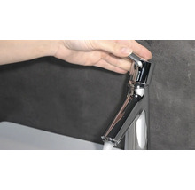Hand betätigt einen Wasserhahn aus Metall.