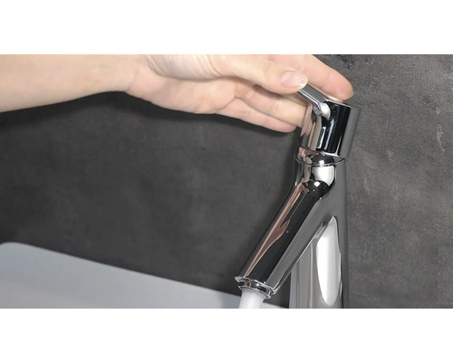 Une main actionne un robinet en métal.