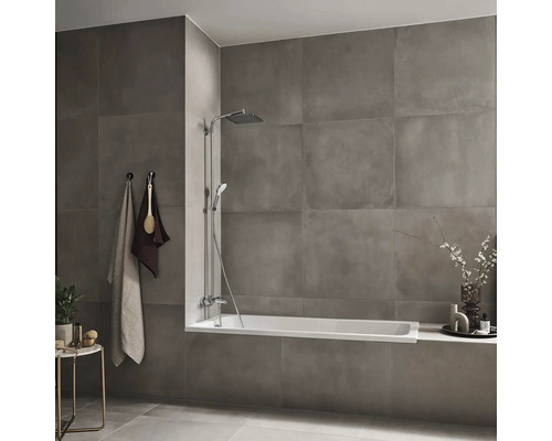 Badezimmer mit Badewanne, Duscharmatur, Handtüchern und Ablagetisch vor grauen Fliesen