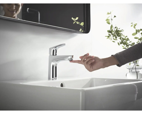 Mitigeur monocommande sur un lavabo dans une salle de bains avec miroir et décoration.