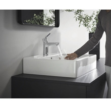Waschbecken mit Armatur und Person, die ein Glas Wasser befüllt