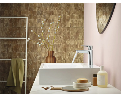Salle de bain moderne avec lavabo, robinet, miroir et éléments décoratifs pour une ambiance élégante.