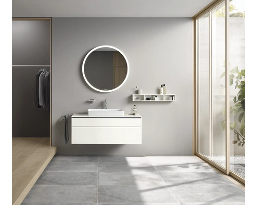 Salle de bains avec lavabo, miroir rond avec éclairage et étagères.