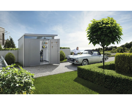 Gartenszene mit Gerätehaus, Oldtimer und Mann bei der Autopflege