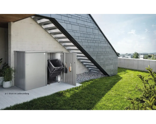 Mülltonnenbox aus Metall mit Mülltonne und Gartengeräte an einer Hauswand mit Außentreppe