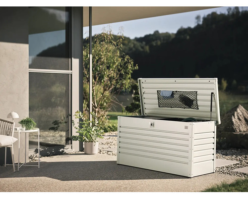 Geöffnete Gartenbox aus Metall auf einer Terrasse mit Gartenblick