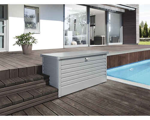 Auflagenbox Biohort 160 High 159 x 79 x 83 cm silber-metallic Aufnahme einer grauen Gerätebox aus Metall auf einer Holzterrasse neben einem Pool.