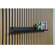 Étagère murale noire devant un lambris en bois avec décoration