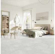 Chambre claire avec lit, coin salon, armoire et décoration sur sol clair