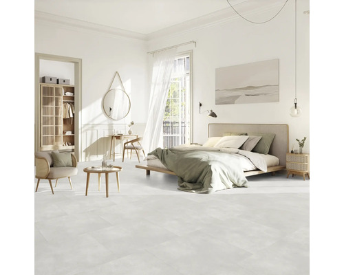 Chambre claire avec lit, coin salon, armoire et décoration sur sol clair