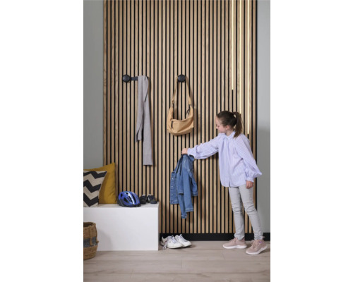 Couloir avec mur en lamelles de bois, patères et enfant