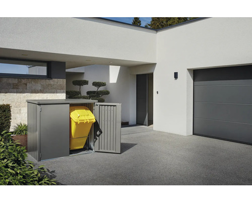 Mülltonnenbox aus Metall mit gelber Mülltonne vor einem modernen Haus