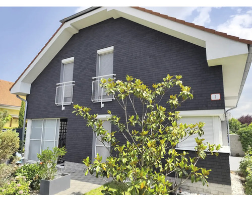 Außenansicht eines Hauses mit Fassade, Fensterrollläden und Bewuchs