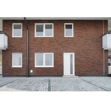 Façade d''une maison avec des murs en briques, des fenêtres blanches et une porte