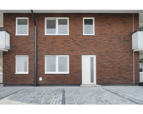 Façade d''une maison avec des murs en briques, des fenêtres blanches et une porte