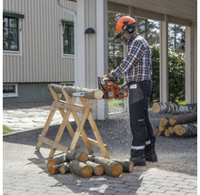 Mann sägt Holz mit einer Kettensäge auf einem Holzbock