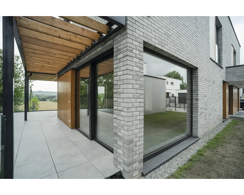 Vue extérieure d''une maison avec des murs en briques, une terrasse et une pergola
