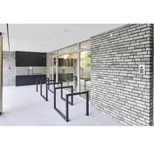 Espace d''entrée d''un immeuble d''habitation avec boîtes aux lettres, range-vélos et un mur en briques
