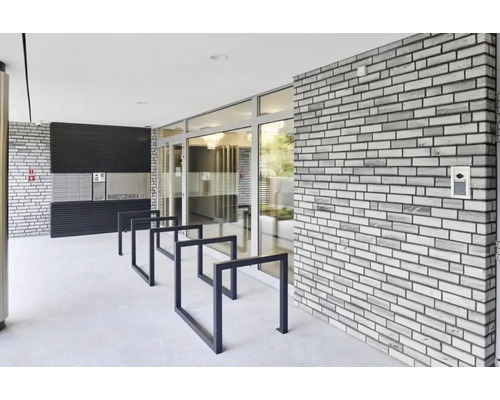 Espace d''entrée d''un immeuble d''habitation avec boîtes aux lettres, range-vélos et un mur en briques