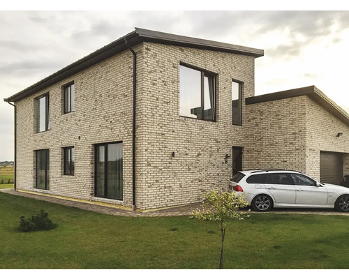 Extérieur d''une maison à deux étages avec garage, façade en briques et pelouse