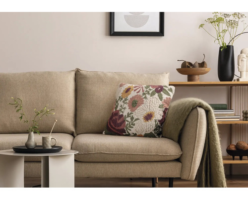 Scène de salon avec canapé beige, coussin décoratif à fleurs et table d''appoint