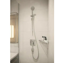 Douche moderne avec douchette à main, robinetterie et étagère dans la salle de bains.