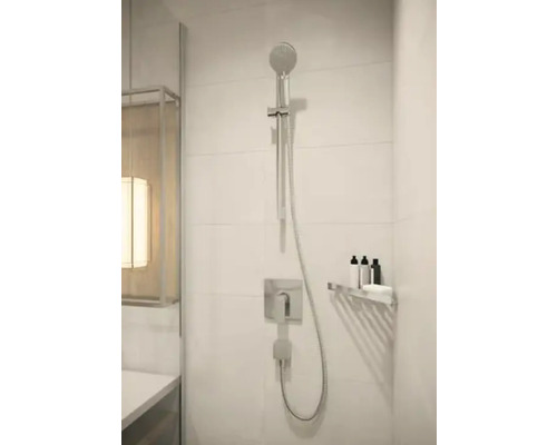 Douche moderne avec douchette à main, robinetterie et étagère dans la salle de bains.