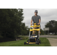Un homme utilise une tondeuse à gazon jaune de marque DeWalt dans le jardin.