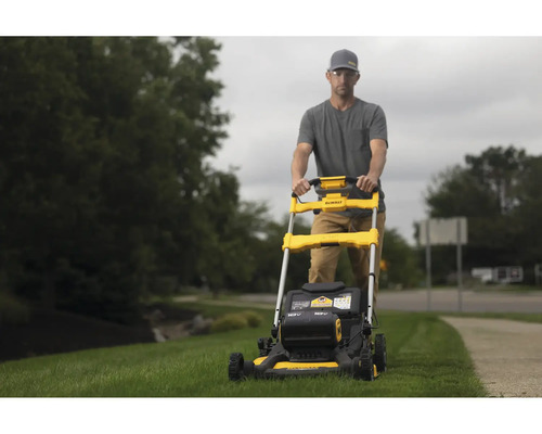 Un homme utilise une tondeuse à gazon jaune de marque DeWalt dans le jardin.