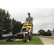 Un homme pousse une tondeuse à gazon jaune et noire dans le jardin.