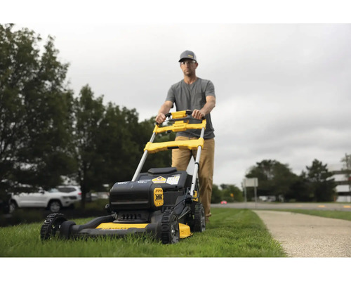 Un homme pousse une tondeuse à gazon jaune et noire dans le jardin.