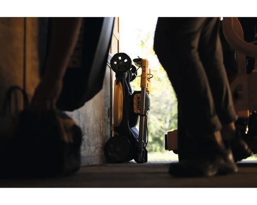 Projecteur de travail DeWalt plié avec roues de transport, rangé dans un atelier