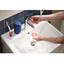 Lavabo avec robinet et eau courante, accessoires de salle de bain en arrière-plan