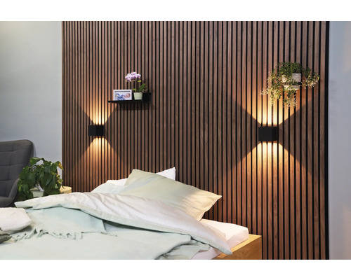 Chambre à coucher avec mur en panneaux de bois, appliques murales, étagère avec décoration et lit
