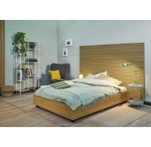 Chambre lumineuse avec lit, table de chevet, étagère et fauteuil
